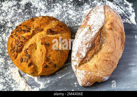 Bakery background with two different freshly baked crispy bread on flour kitchen table Stock Photo