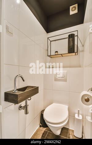 a toilet and sink in a small bathroom with tiled walls, white tiles and dark wood trim around the wall Stock Photo