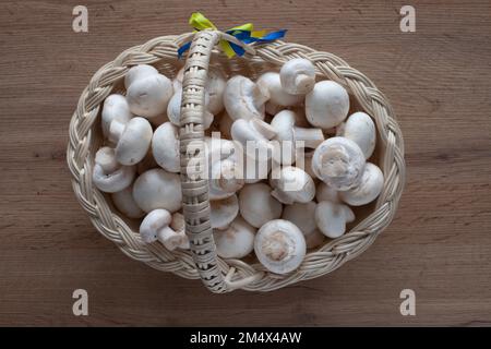 Champignon mushrooms in a basket on the table. Top view of vegetables. Stock Photo