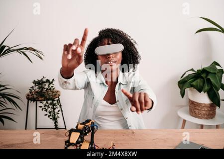 Young engineer wearing virtual reality headset and gesturing at home office Stock Photo