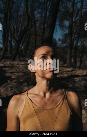 Thoughtful woman standing in burnt forest Stock Photo
