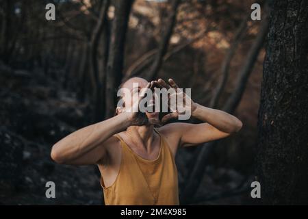 Woman shouting with dirty hands in burnt forest Stock Photo