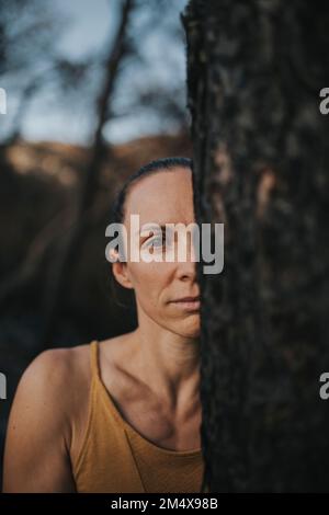 Woman standing by burnt tree in forest Stock Photo