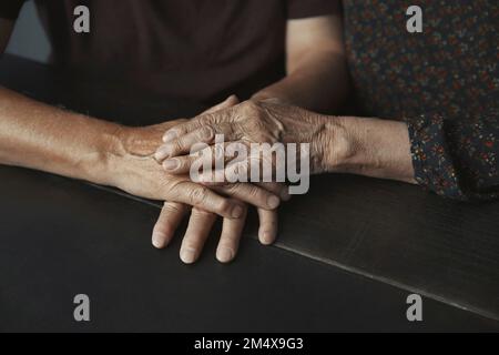 Senior couple stacking hands on table Stock Photo