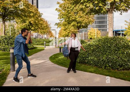 Young man photographing woman standing at park Stock Photo