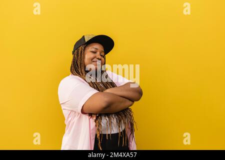 Confident young woman with arms crossed standing in front of wall Stock Photo