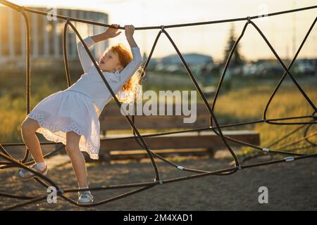 Girl climbing rope ladder in park Stock Photo