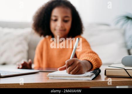Girl with pen and notepad doing homework at home Stock Photo