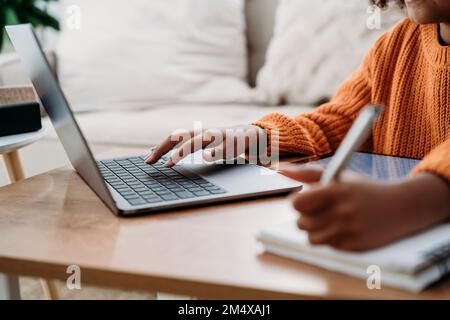 Hands of girl using laptop and doing homework at home Stock Photo