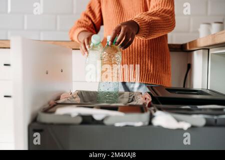 Hands of girl putting plastic bottles in recycling bin at home Stock Photo