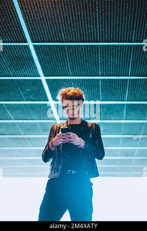 Young man wearing smart glasses using mobile phone at underpass Stock Photo