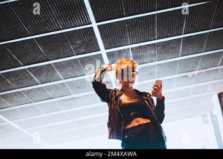 Woman using mobile phone at underpass Stock Photo
