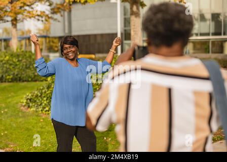 Man photographing cheerful woman gesturing at park Stock Photo