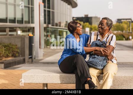 Senior couple laughing with each other sitting on bench Stock Photo