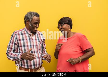 Happy senior couple dancing against yellow background Stock Photo