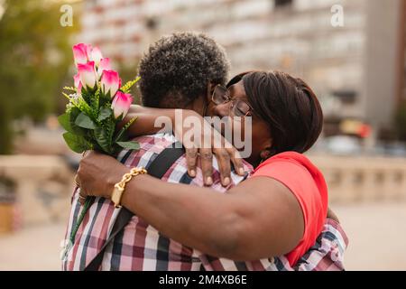 Woman with bunch of flowers embracing man Stock Photo