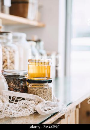 Mason jars in mesh bag on table at zero waste store Stock Photo