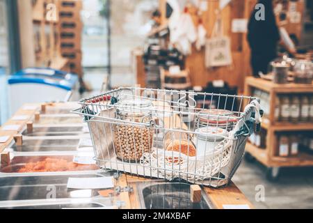 Mason jars filled with food in shopping basket on counter at shop Stock Photo