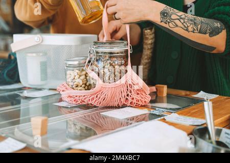 Woman holding mesh bag with mason jars in shop Stock Photo