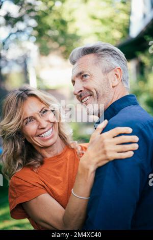 Cheerful mature man and woman embracing and having fun together in back yard Stock Photo