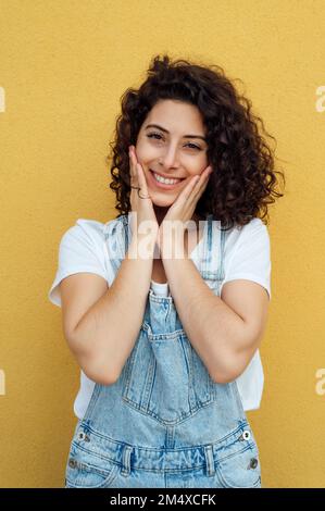 Beautiful smiling woman in front of yellow wall Stock Photo