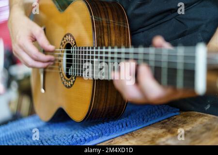 Luthier checking strings of guitar in workshop Stock Photo