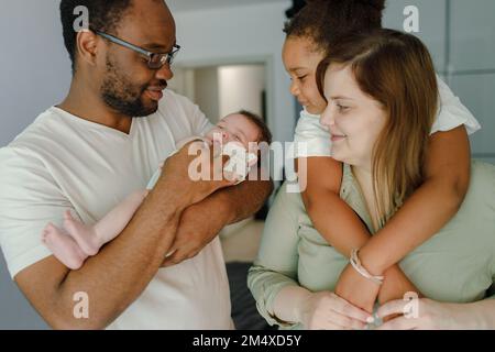 Happy father and mother spending time with daughters at home Stock Photo