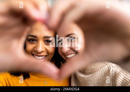 Happy women making heart shape gesture Stock Photo