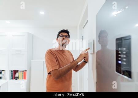 Young man using smart home device on wall Stock Photo