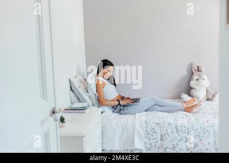 Girl using laptop and studying in bedroom Stock Photo