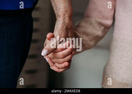Grandmother holding granddaughter's hand at home Stock Photo
