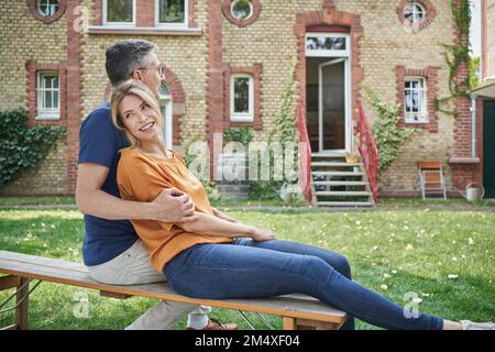 Happy woman leaning on man in garden Stock Photo