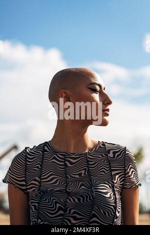 Woman with shaved head in front of sky Stock Photo