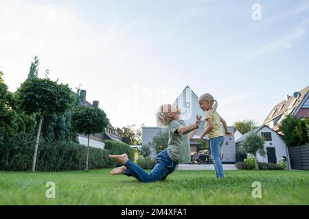 Girl with brother playing in garden Stock Photo