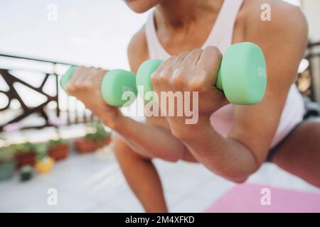 Woman doing exercises with dumbbells on the terrace Stock Photo