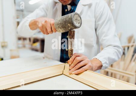 Hands of craftsman using work tool to make frame in workshop Stock Photo