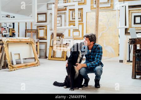 Black dog with mature man in workshop Stock Photo