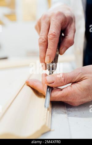 Craftsman carving wooden frame in workshop Stock Photo