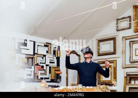 Mature man using virtual reality simulator gesturing in workshop Stock Photo