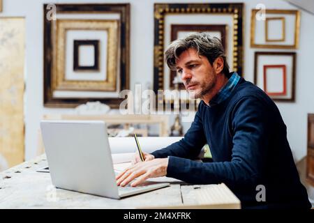 Mature man using laptop working in workshop Stock Photo