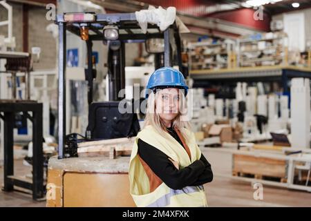 Confident engineer standing with arms crossed in factory Stock Photo
