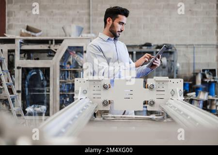 Engineer using tablet PC standing by machinery at industry Stock Photo