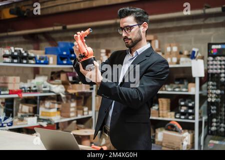 Businessman examining robotic arm at industry Stock Photo