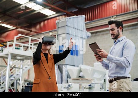 Businessman using tablet PC with colleague gesturing by wearing virtual reality simulator Stock Photo