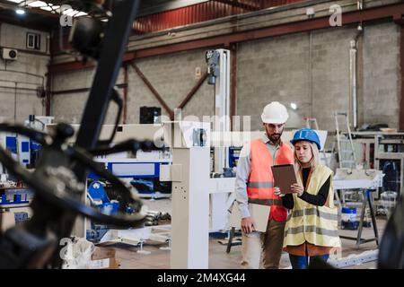 Engineer with colleague using tablet computer at industry Stock Photo