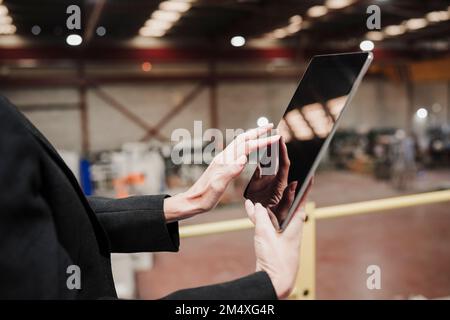 Hands of mature businesswoman using tablet computer at industry Stock Photo