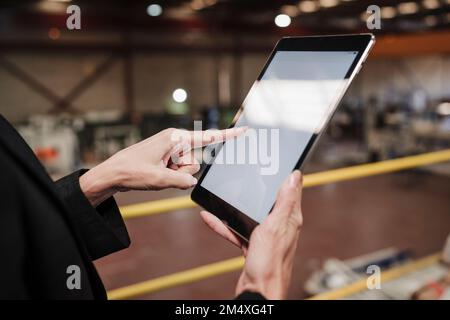Hand of businesswoman using tablet PC at factory Stock Photo