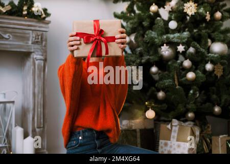 Woman holding Christmas present at home Stock Photo