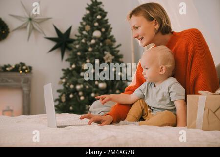 Mother with son using laptop on bed in bedroom Stock Photo