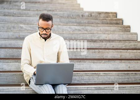 Freelancer using laptop sitting on steps Stock Photo
